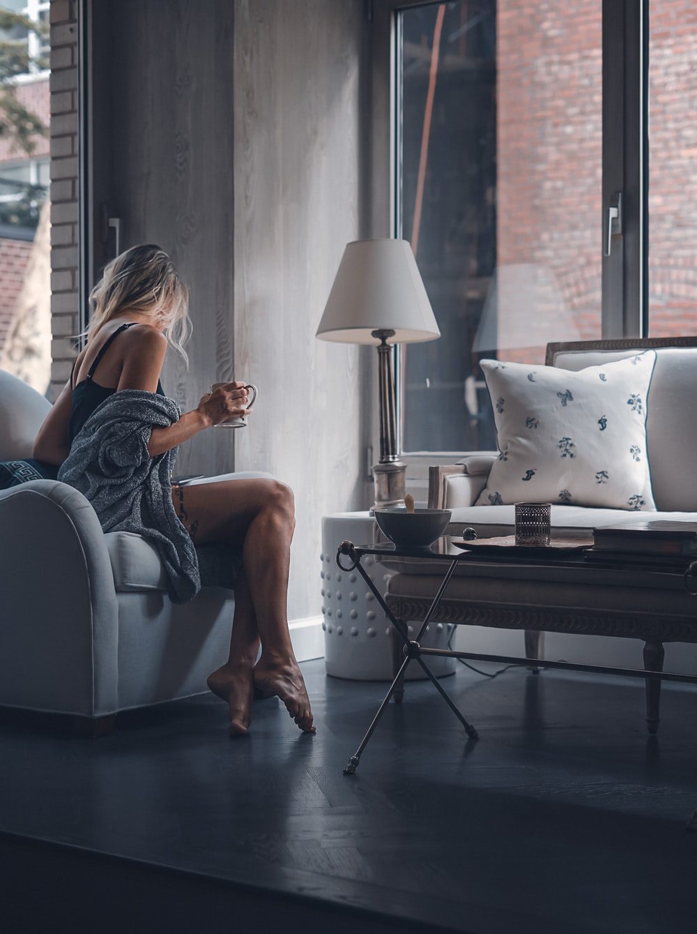 Girl sitting with a coffee on a grey floor