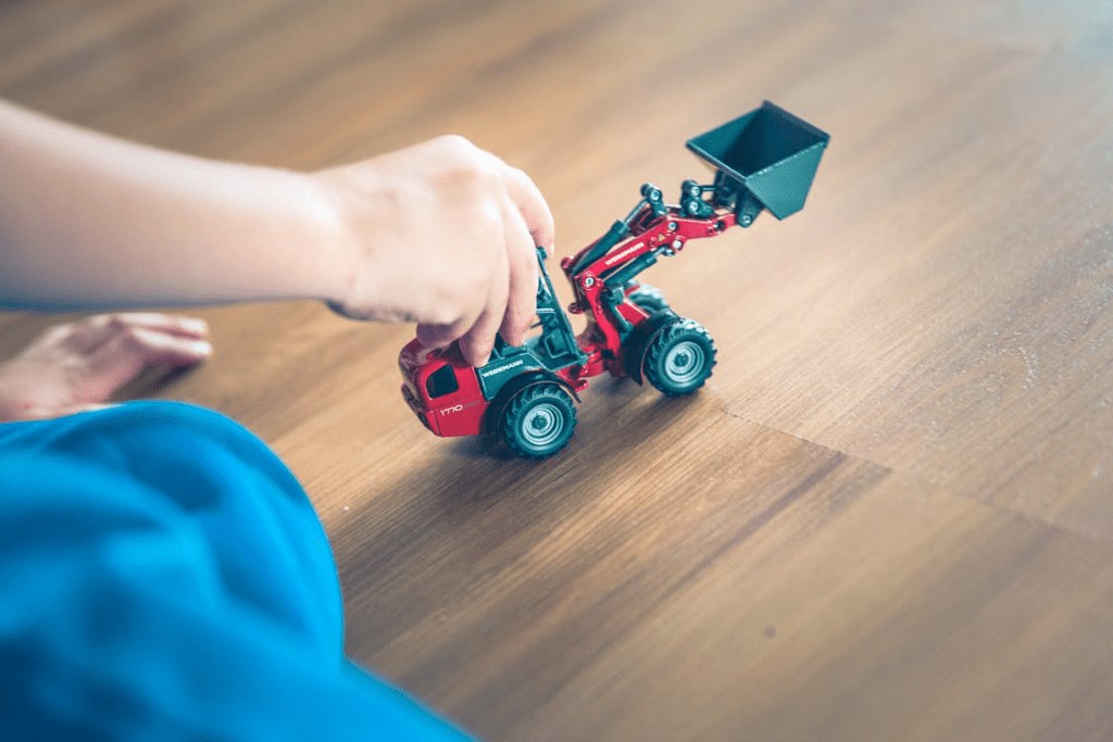 Kid playing on wood floor with a tractor
