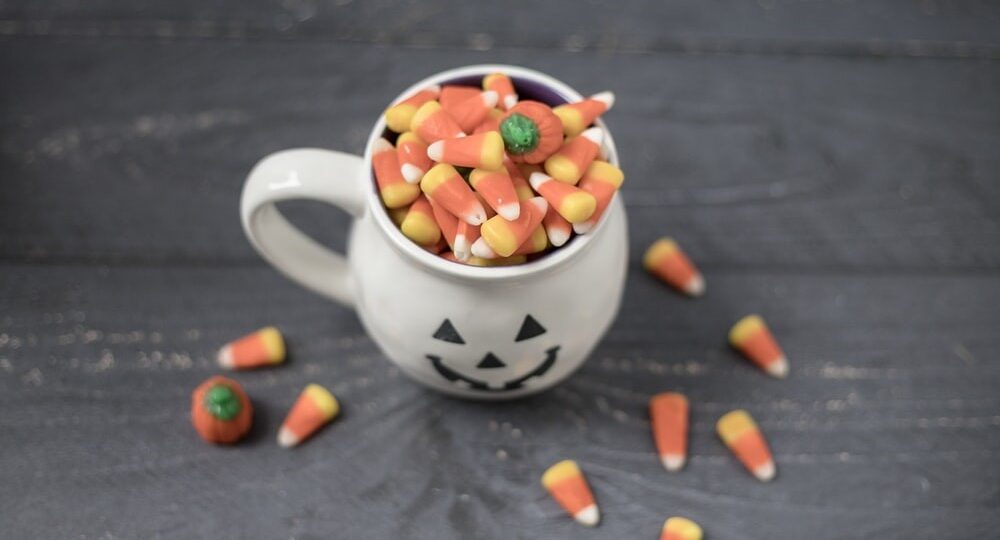 Halloween mug full of candy corn on a wooden floor
