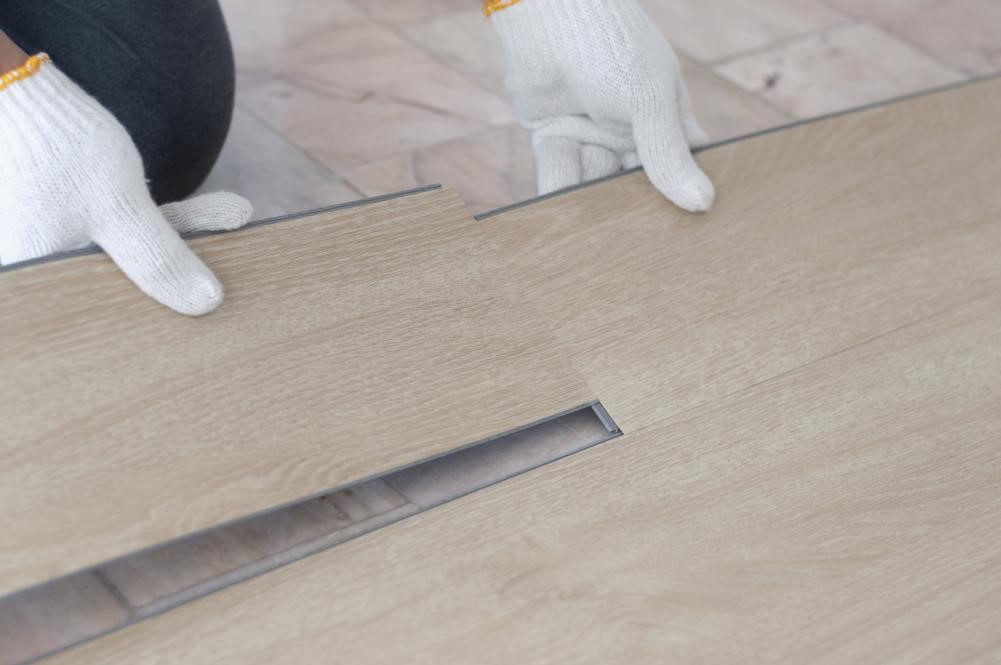 A flooring specialist installing vinyl tiles that mimic the look of hardwood.